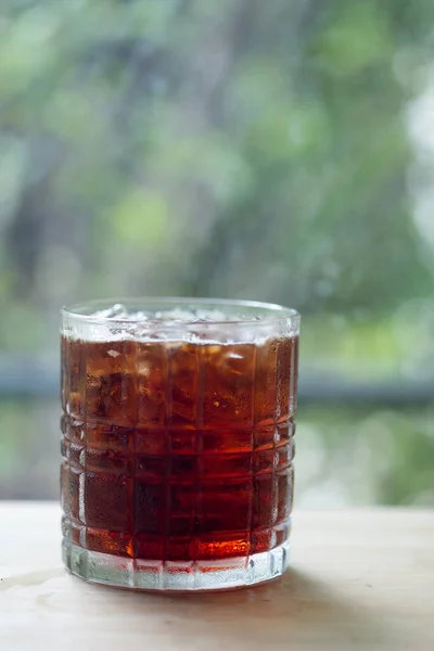 A glass of iced black coffee in glass on the table in cafe