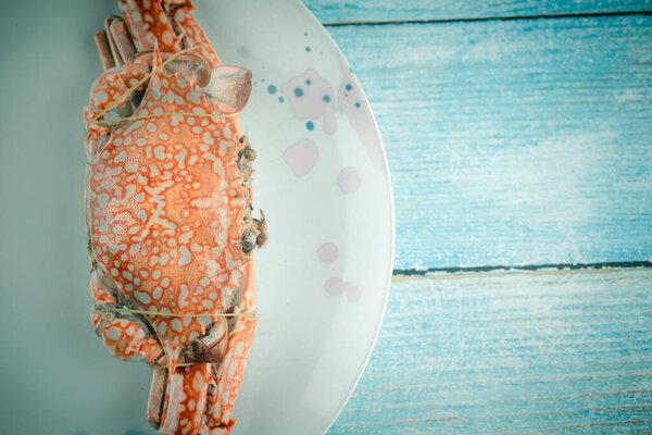 Steamed crabs in Thai style on dish and blue wooden background