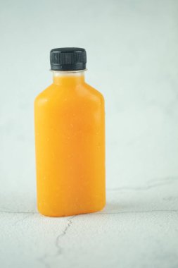 Beton beyaz arka planda portakal suyu şişelenmiş (sağlıklı içecek)