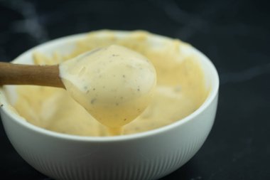Beyaz kaseden kaşık kaşık dolusu sezar salatası sosu kullan.