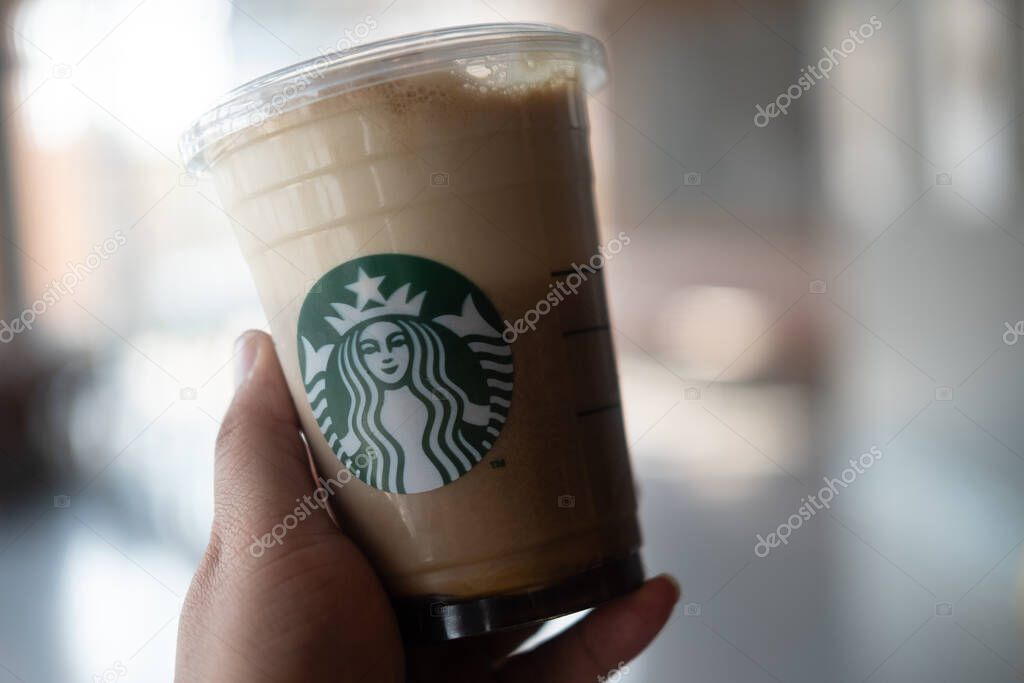 Bangkok, Thailand - June 7, 2020: Sparkling nitro cold brew coffee shot in ready to drink at Starbucks Store cafe in hand. Starbucks coffee brand logo on Nitro americano coffee cold brew beverage