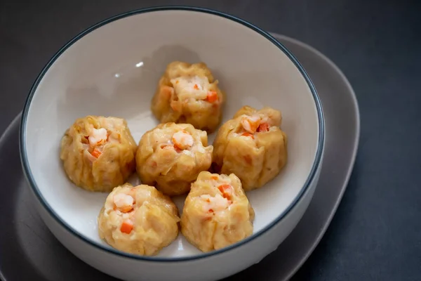 Homemade Chinese steamed shrimp dumpling or Shumai in bowl on a black background