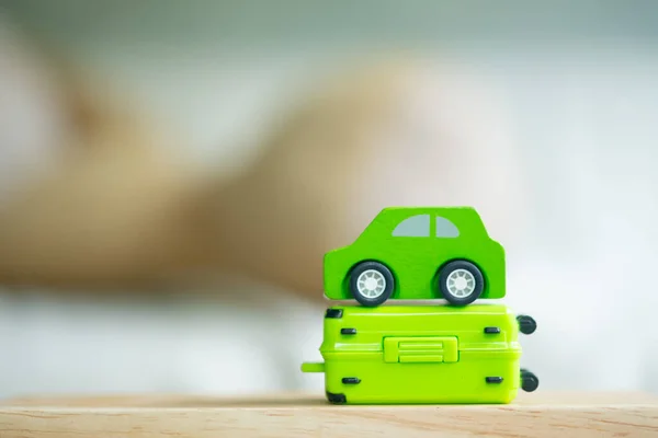 Miniature green car on miniature green suitcase. Concept of travel