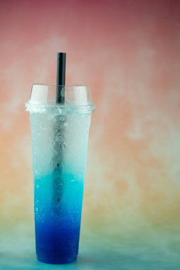 Pastel arka planda mavi italyan gazozlu uzun bir plastik bardak. Yaz içeceği