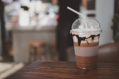 Kahve dükkanının ahşap masasına koyulan plastik bardakta buzlu kahve.