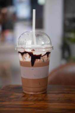 Kahve dükkanının ahşap masasına koyulan plastik bardakta buzlu kahve.