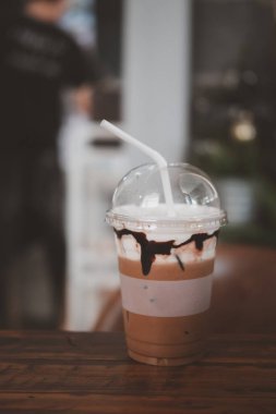 Kahve dükkanının ahşap masasına koyulan plastik bardakta buzlu kahve.