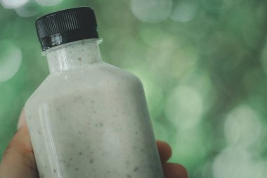 Elinde plastik şişeyle çeşitli fındıklı smoothie karışımı. Sağlıklı içki konsepti