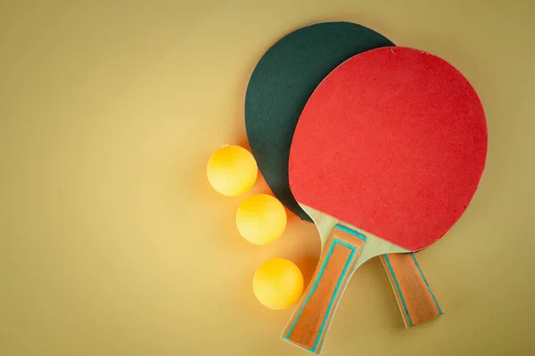 Ping pong paddles and ball on orange background with copy space
