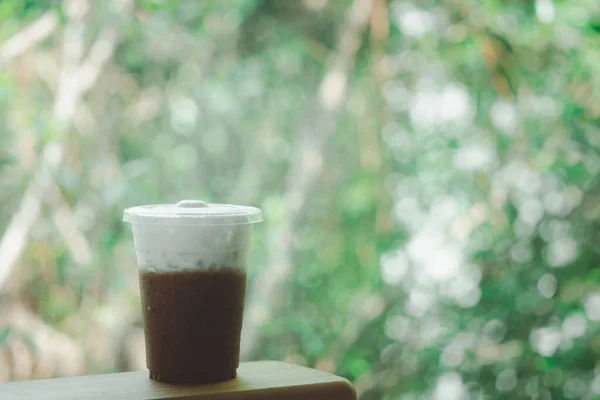 Iced Mocha coffee in takeaway glass and milk foam with nature background. Show Layer milk foam and coffee