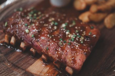 Ahşap bir tahtanın üzerinde barbekü sosuyla ızgara domuz pirzolası.