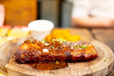 Ahşap bir tahtanın üzerinde barbekü sosuyla ızgara domuz pirzolası.