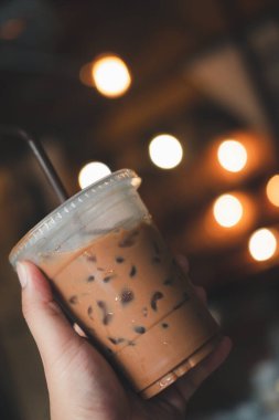 Hafif bulanık arkaplanda el ele tutuşan buzlu kahve. Tazeleyici içecek.