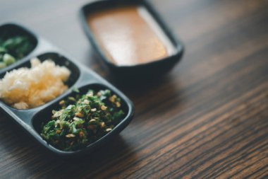 Dilimlenmiş sebze, sarımsak, soğumuş soğan ve soğumuş soğuklar Shabu stilinde sos için siyah tepside.