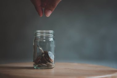 El cam şişeye bozuk para koyuyor, el de cam şişeye bozuk para koyuyor. Gelecek konsept için para biriktirme.