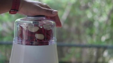 Tayland yemeği yapmak için kırmızı biber ve sarımsağı karıştırıcıya koy.