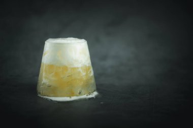 Küçük bardakta soğuk köpüklü bira ve mesaj için boş alan olan siyah arka plan.