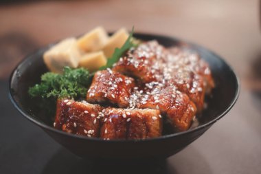 Siyah kasede pilavın üstünde ızgara yılan balığı. Japon unagi mutfağı.