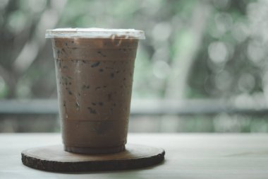 Ahşap masanın üzerinde plastik camlı buzlu siyah çikolata.