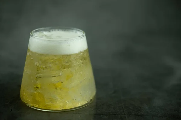 小さなガラスと黒の背景に泡と冷たいビール — ストック写真