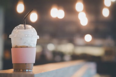 Buzlu kapuçino ve süt köpüğü pembe kağıt kollu paket servis bardağında.