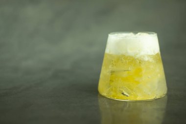 Küçük bardakta köpüklü soğuk bira ve metin için boş alan olan siyah arka plan.