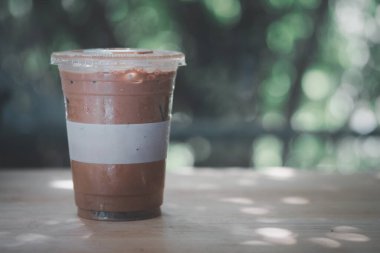 Ahşap masada plastik bardakta buzlu Mocha kahvesi.
