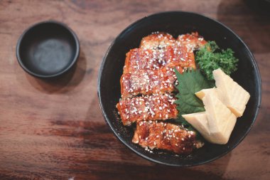 Siyah kasede pilavın üstünde ızgara yılan balığı. Japon unagi mutfağı.