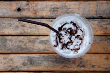 Tahta masadaki çikolata soslu buzlu sütün en üst görüntüsü..