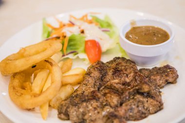 Biber soslu domuz eti, salata ve patates kızartması.