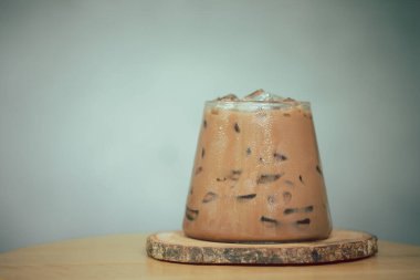 Kahve dükkanında bir bardak buzlu mocha üzerine ahşap çay tabağı.