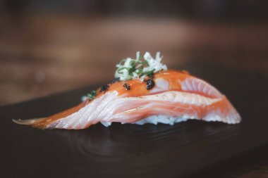 Sos soslu ızgara somon balığı ve siyah tabakta servis edilen siyah havyar.