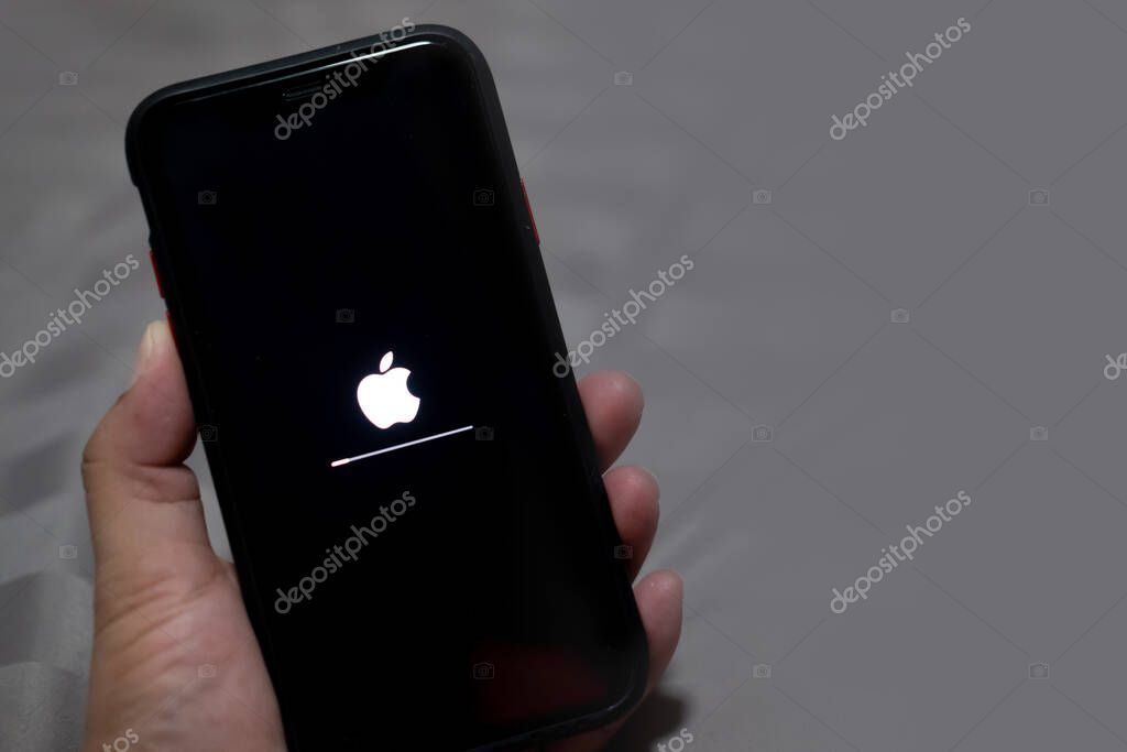 Bangkok, Thailand - August 26, 2020 : Close up hand holding apple icon and status bar on screen operation software update new version