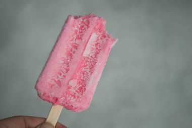 Bir ısırıkla lezzetli çilekli dondurma tutuyorum. Kapat.