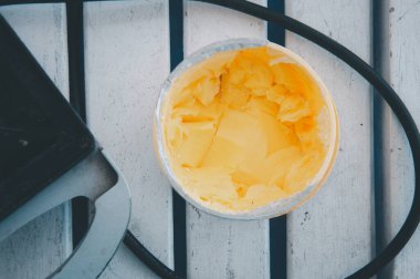 Beyaz ahşap masada plastik kabın içinde yumuşak tereyağı
