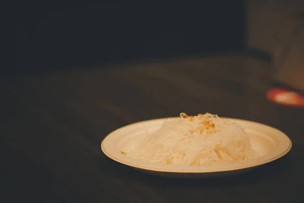 Fried dried rice vermicelli (rice noodle) on paper dish on wood table