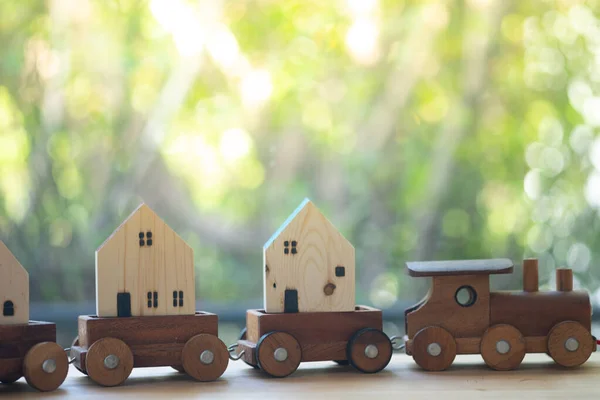 Miniature wooden home on wood toy train. Concept of move home and business real estate concept