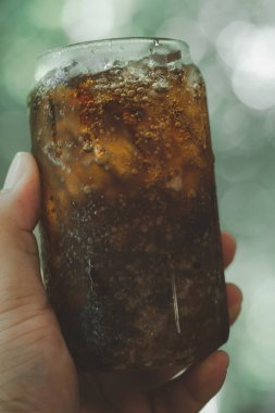 Doğa kökenli, el ele tutuşan bir bardak meşrubat.