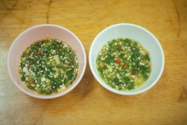 Tahta masadaki iki kâseye Tayland deniz ürünleri sosu.