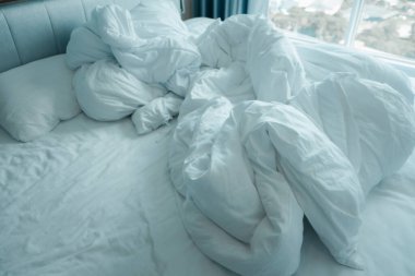 Sabah ışıklarıyla dolu dağınık bir yatak. Yeni uyanma kavramı.