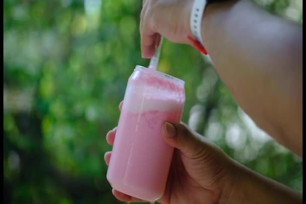 Крупным Планом Руки Перемешивающей Розовый Молочный Коктейль Соломой Стакане — стоковое видео