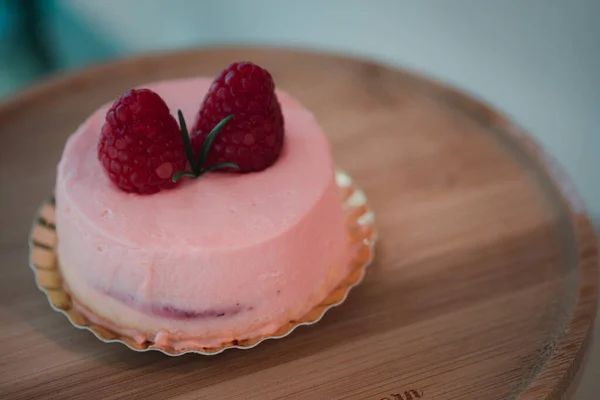 粉红的慕斯蛋糕 上面涂满了粉红色的奶油 顶部是浆果 放在一个圆形的木架上 — 图库照片