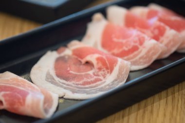 Siyah tepside taze domuz eti Shabu, sukiyaki ya da Japon yahnisi için pişmeye hazır. Seçici odak.