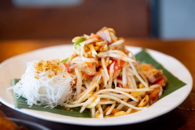 Tayland baharatlı yeşil papaya salatası ya da ızgara domuz boyunlu ve pirinç vermicelli soslu Somtum karışımı.