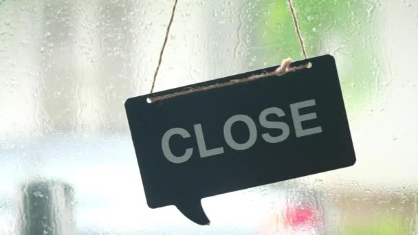 石の雨の背景の間にガラスのドアにオープンの木製のハンギングサイン — ストック動画