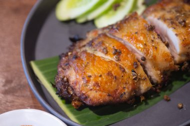 Tayland usulü ızgara tavuk, dilimlenmiş salatalık ile ahşap masada servis edilir. Odaklanmayı seç