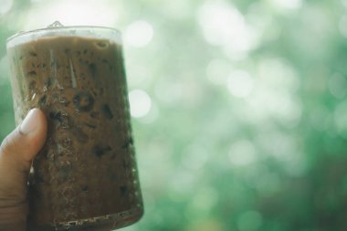 Buzlu kahve bardağını tutan el adamı yeşil arka planda mocha.