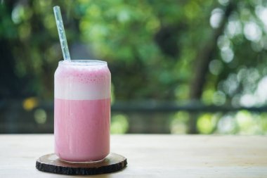 Bardakta pembe süt, ahşap masada yaz için lezzetli bir içecek.