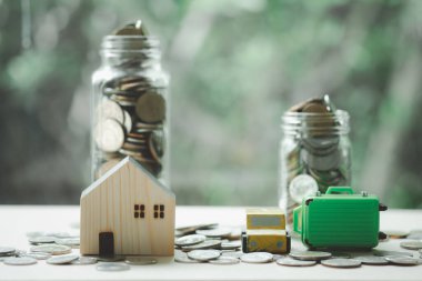 Minyatür ev, ahşap oyuncak ve içinde para olan minyatür yeşil bavul. Para biriktirme kavramı