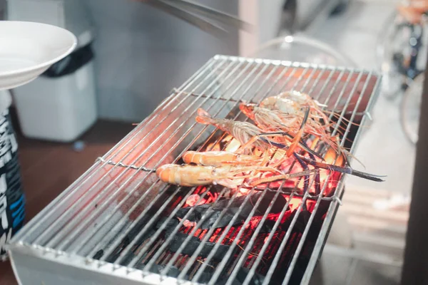 Grilling fresh shrimps on flaming barbecue grill, dinner outdoors